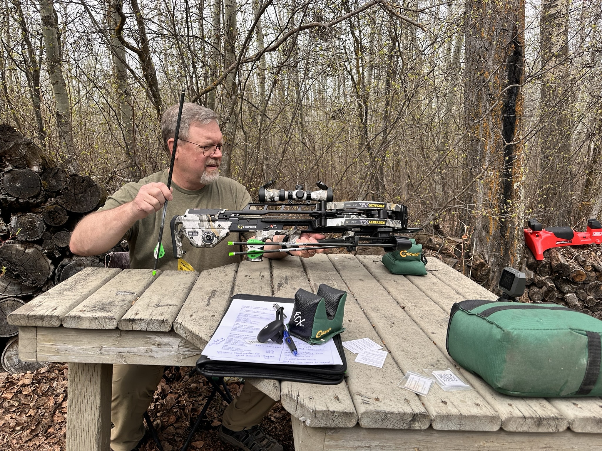 Brad Fenson in a forest holding a camouflaged bow, preparing to shoot, 