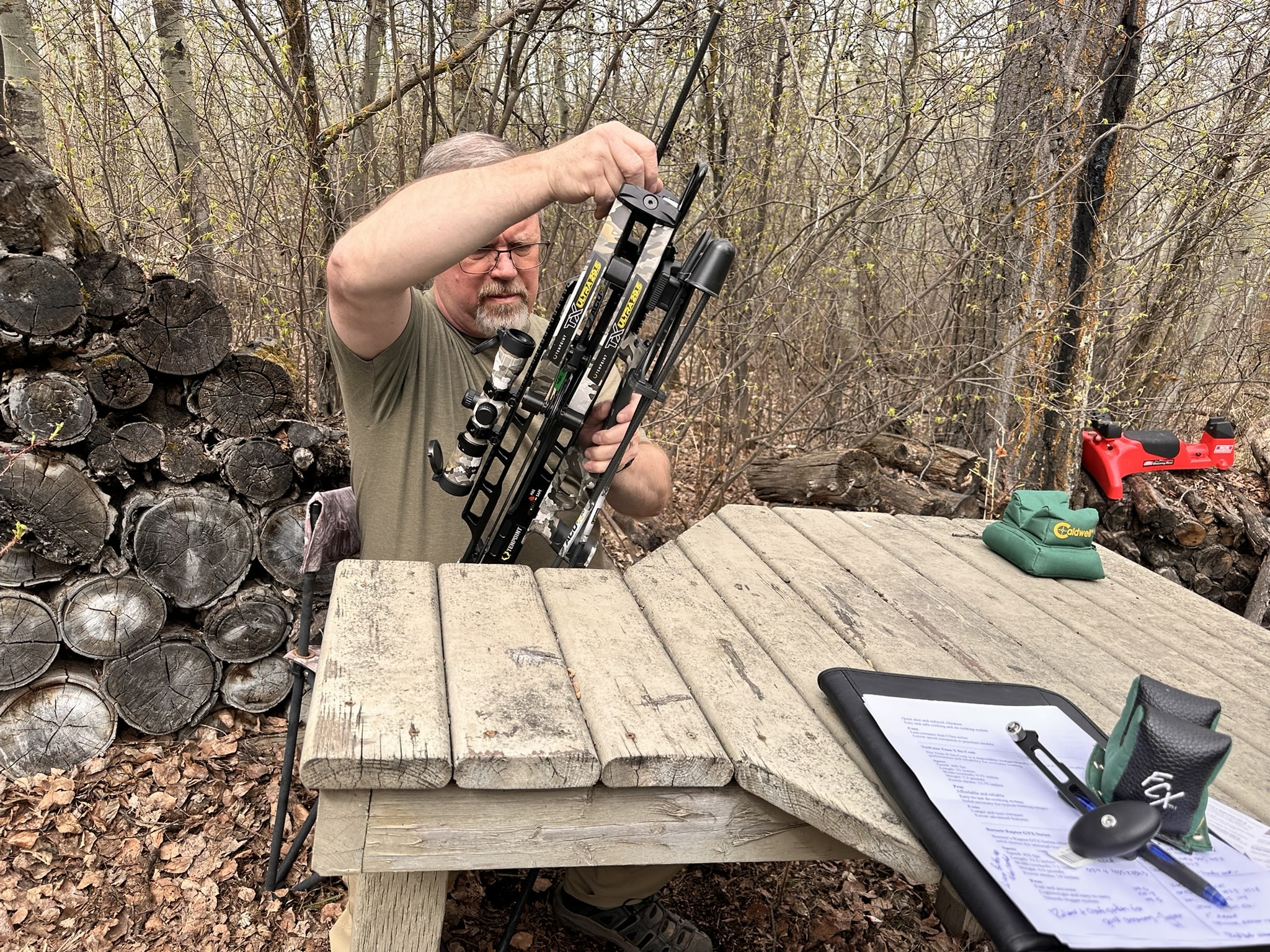 Brad Fenson in a forest holding a camouflaged bow, preparing to shoot, 