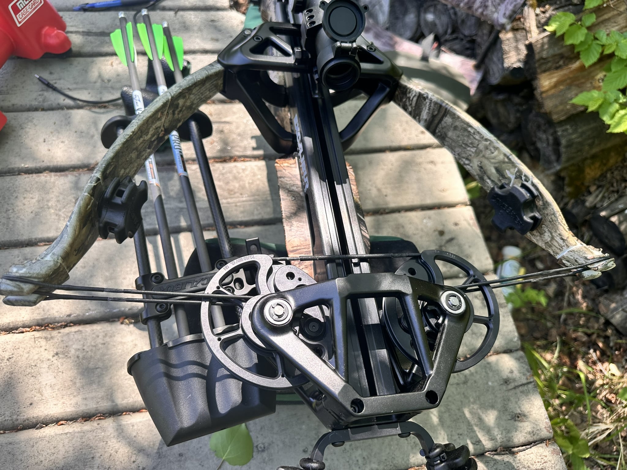 Excalibur crossbow on a weathered table with neon-green fletched arrows nearby outdoors.