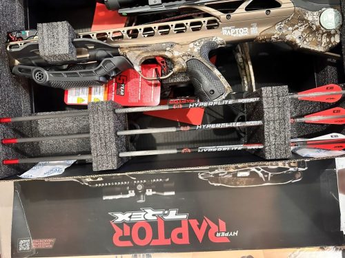 Barnett TRex camouflage-patterned crossbow in foam packaging with a scope and orange bolts nearby.